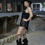 Fashionable woman in edgy attire poses confidently in urban area.